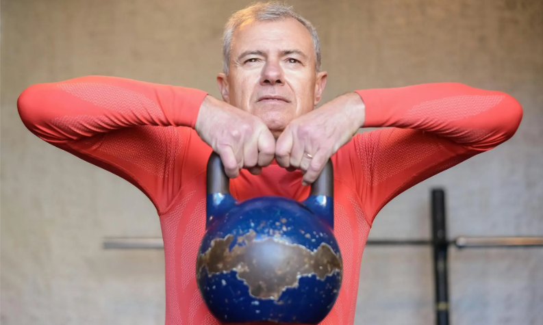 Man over 50 building grip strength with a kettlebell for better mental health.”
