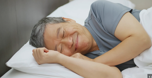 “Older man sleeping peacefully in bed, representing the benefits of quality rest for wellbeing after 50.”