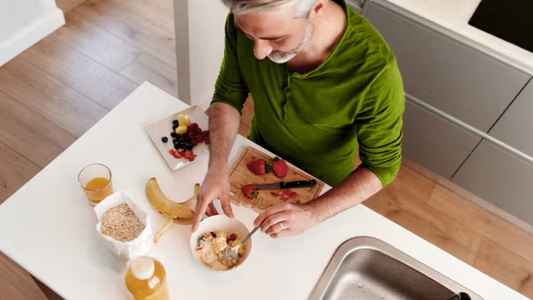 Active man over 50 making a balanced breakfast of oats, yoghurt and fresh fruit to support morning energy.