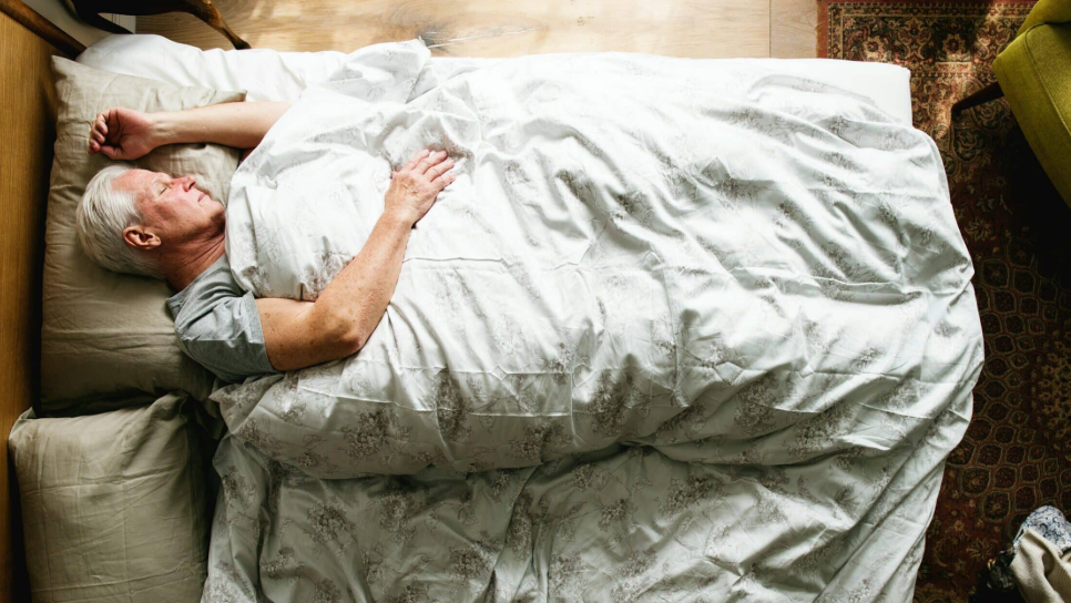 “Man in his 50s sleeping peacefully in a modern bedroom, illustrating midlife snoring and sleep health.”