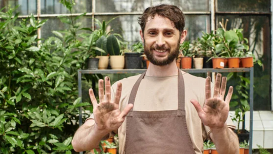 “Man in his 50s painting in the garden, smiling — embracing imperfection and joy.”